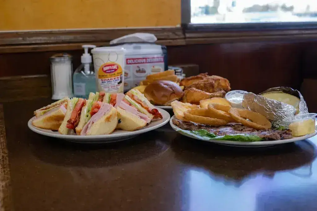 A club sandwich plate and a steak plate with onion rings and a baked potato at Harry's Cafe, Katella Ave, Stanton, CA