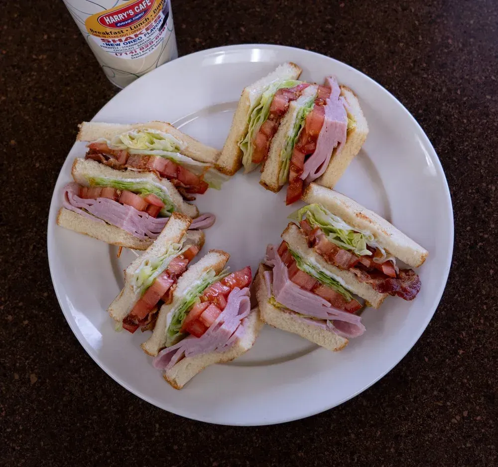 A club sandwich cut in quarters on a white plate at Harry's Cafe, Katella Ave, Stanton, CA