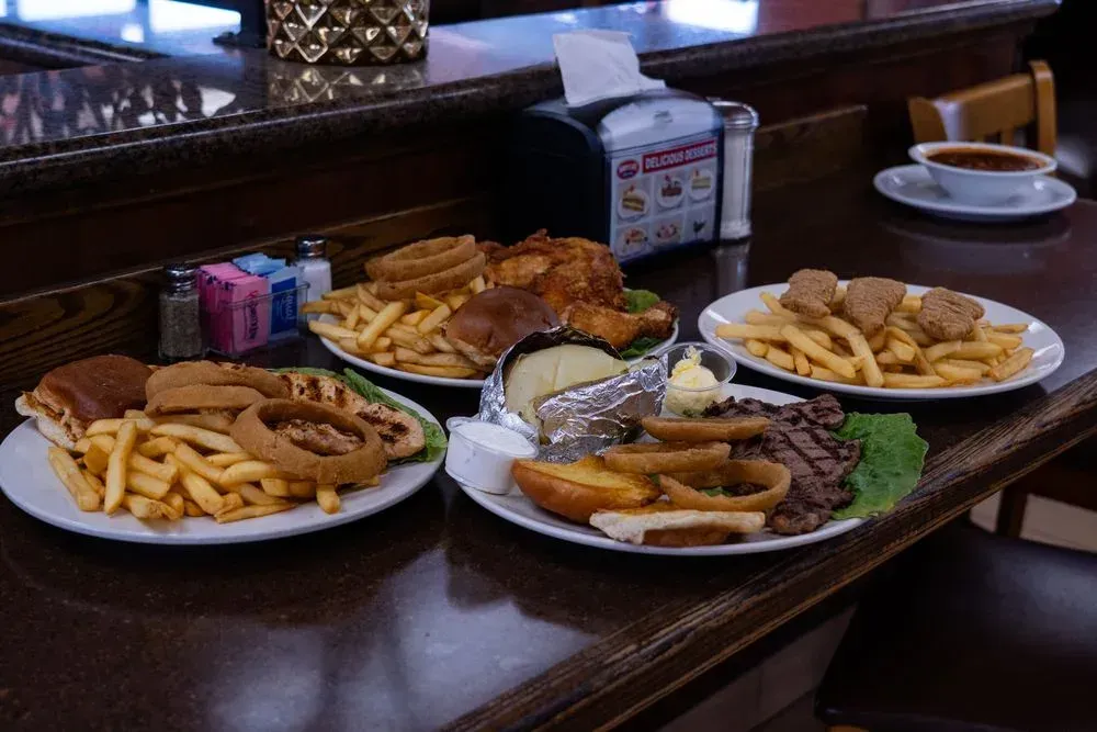 Burger, broasted chicken, steak and chicken tender plates on the counter at Harry's Cafe, Katella Ave, Stanton, CA