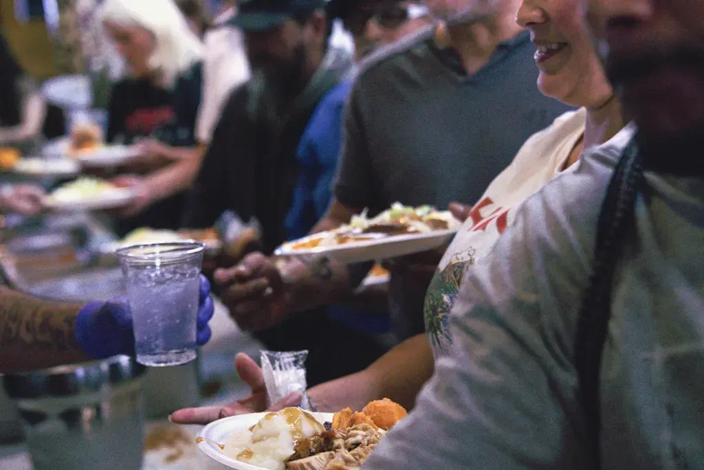 A volunteer serving a free Thanksgiving plate to a customer at the Harry's Cafe restaurant, Katella Ave, Stanton, CA