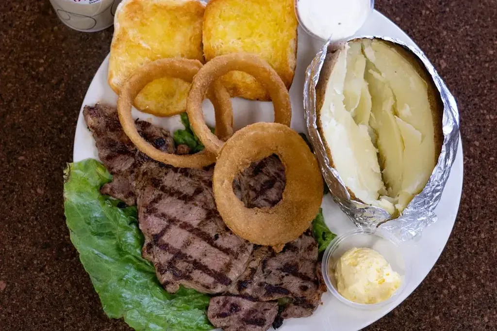 A grilled steak dinner with a baked potato and onion rings at Harry's Cafe, Katella Ave, Stanton, CA
